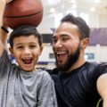 Un père et son fils prennent un selfie sur un terrain de basket