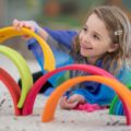 Une fille joue avec un arc-en-ciel en bois